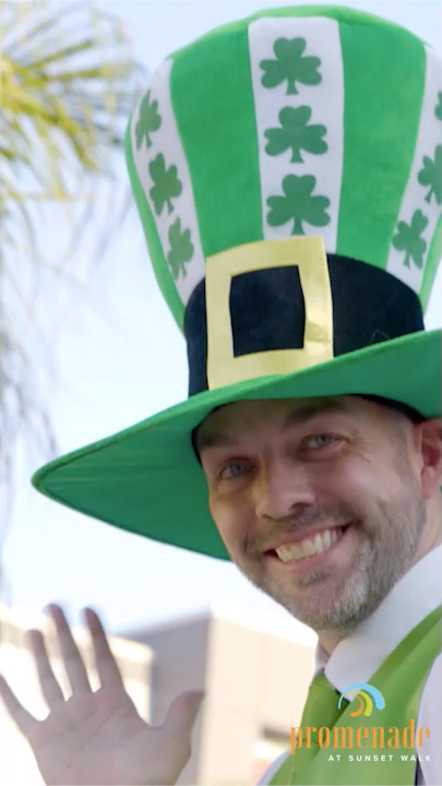 A St. Patrick’s Day stilt walker dressed like a leprechaun smiles and waves.