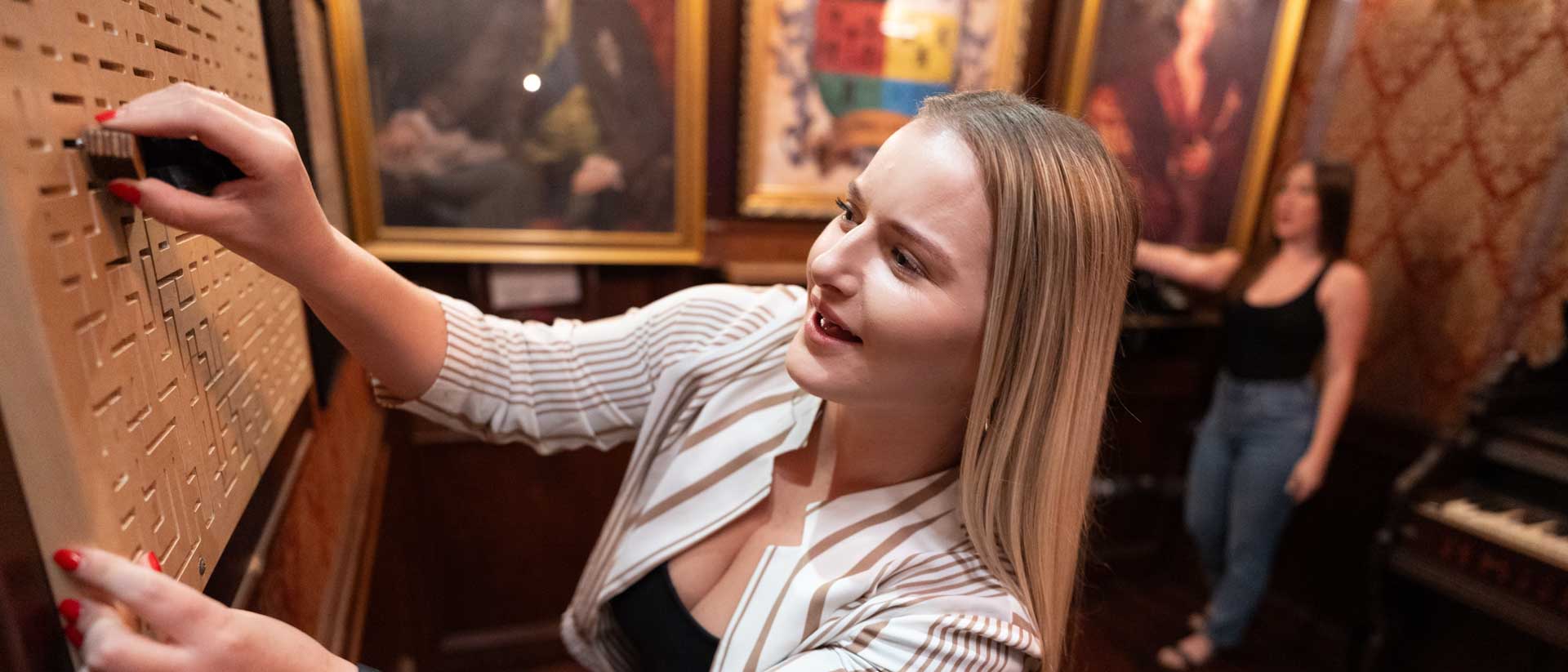 Woman navigating a framed maze on the wall of an Escapology escape room