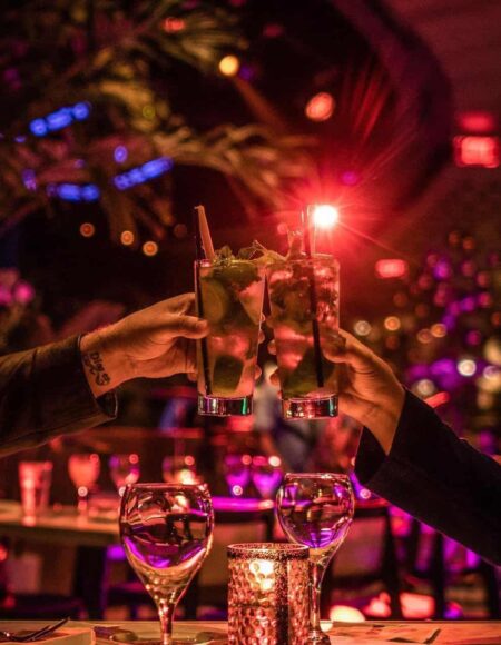 Drinks in glasses raised in a toast at Estefan Kitchen Orlando