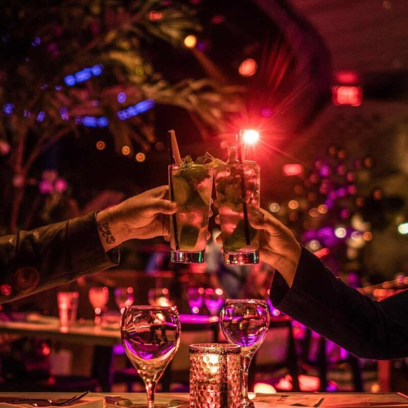 Drinks in glasses raised in a toast at Estefan Kitchen Orlando