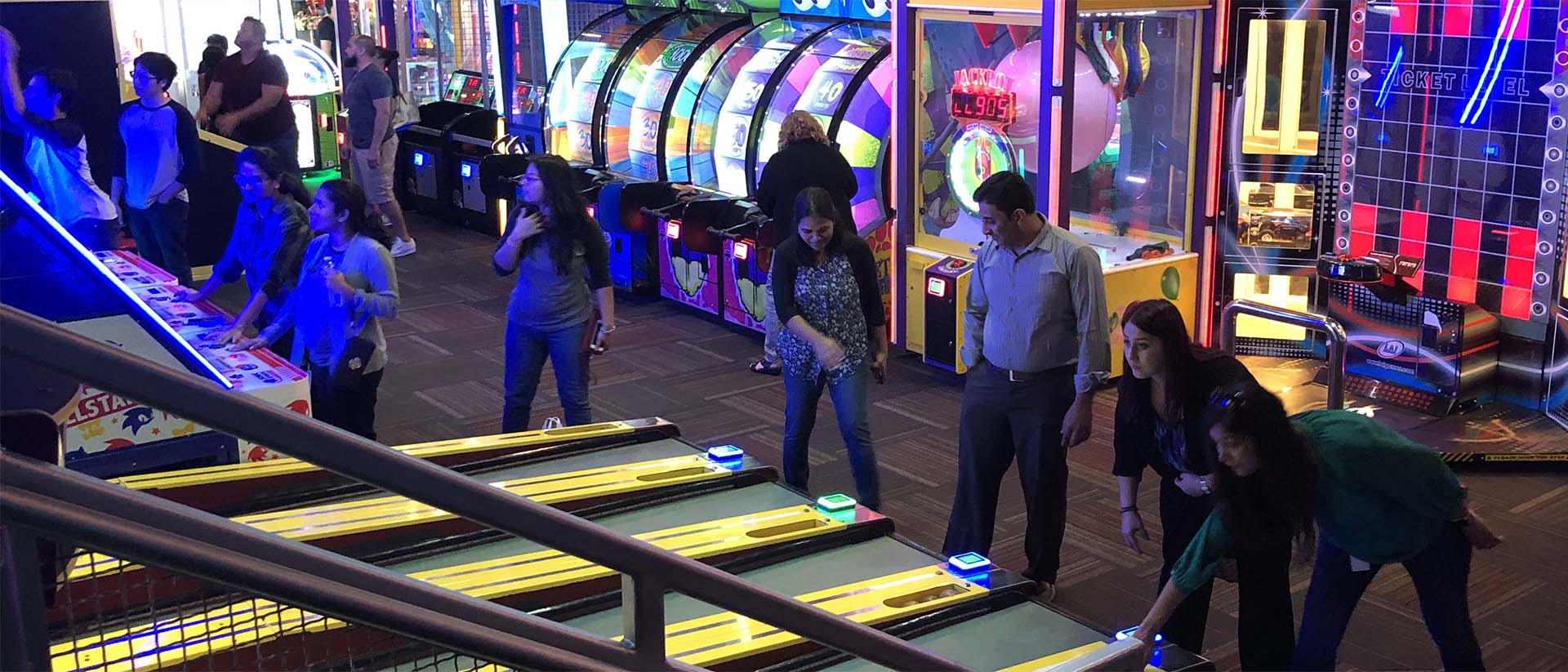 Friends playing Skee Ball at GameTime Kissimmee on the Promenade at Sunset Walk