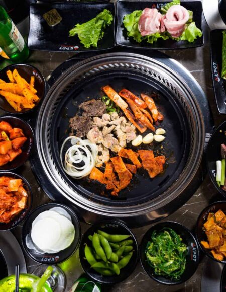 Pot of meat and vegetables surrounded by dishes of ingredients from KPOT Korean BBQ