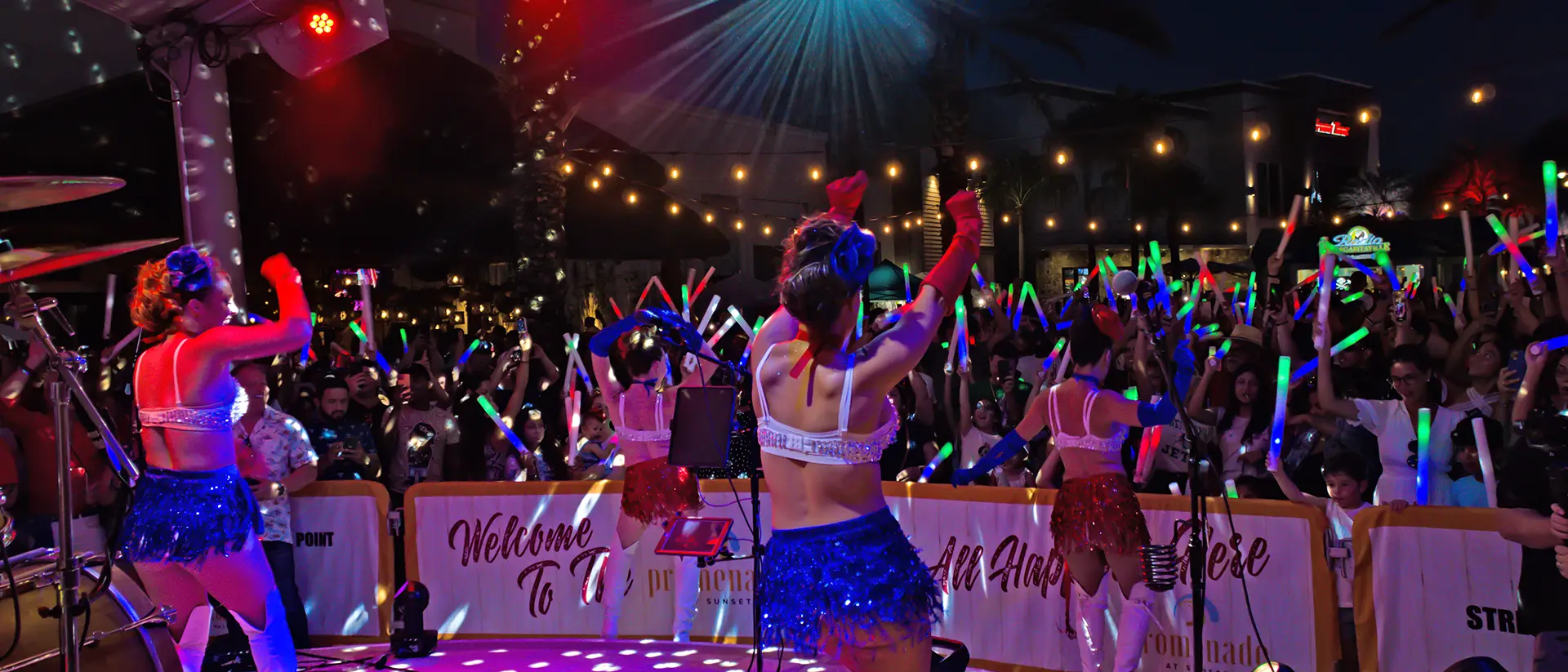 Dancers pump up a crowd with glow sticks during a 4th of July street party
