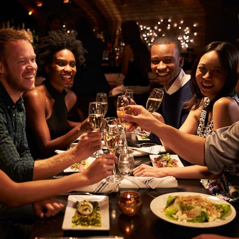 Group dining at a restaurant raising glasses of champagne in a toast