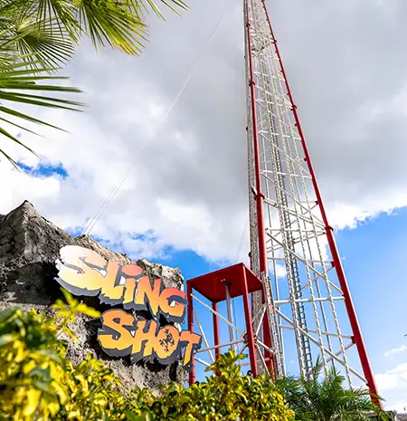 Sunset Walk Slingshot sign in front of one of the thrill ride’s giant arms
