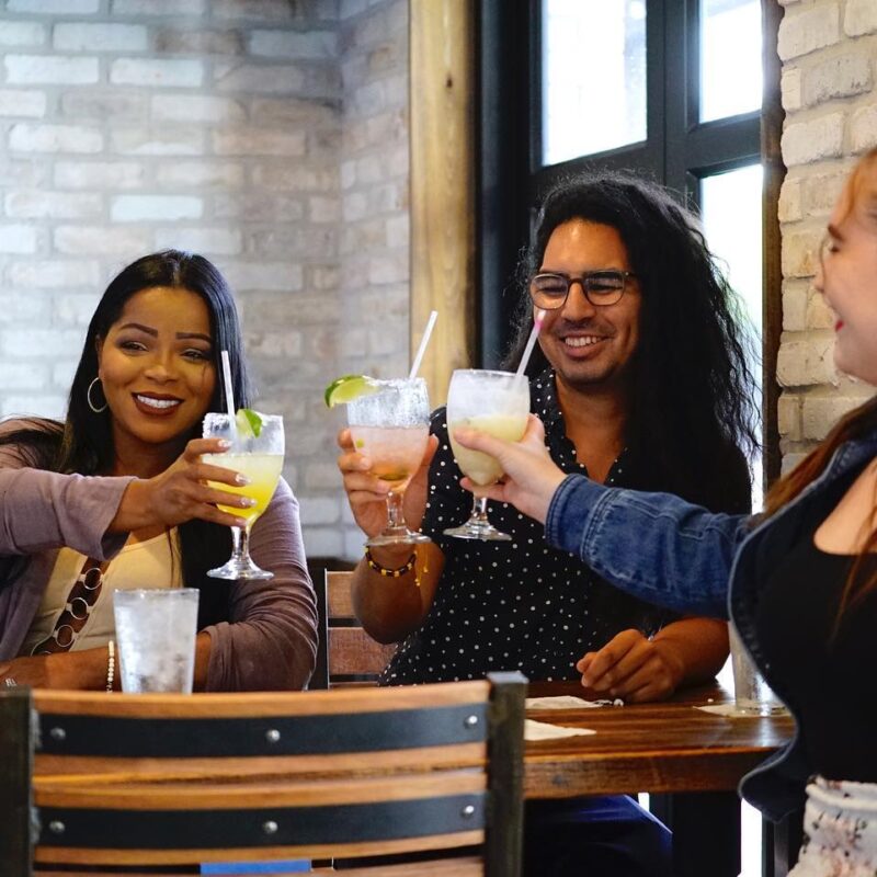 Friends raising drink glasses in a toast at El Jefe Tequilas Taco Cantina