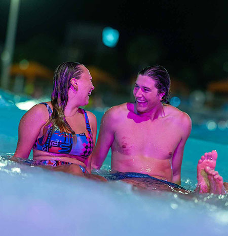 Happy couple sitting in a pool at night at Island H2O Water Park