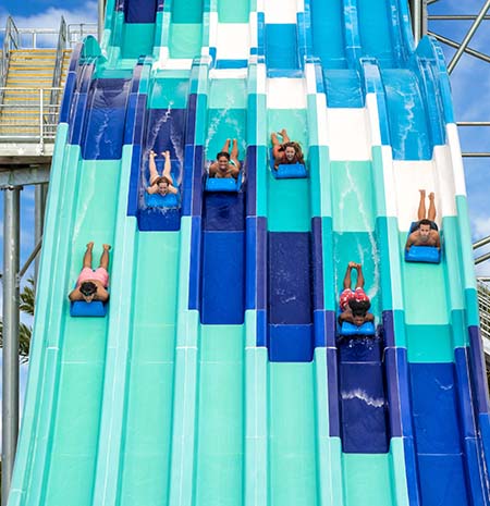 Group of people racing down a waterslide on mats at Island H2O Water Park