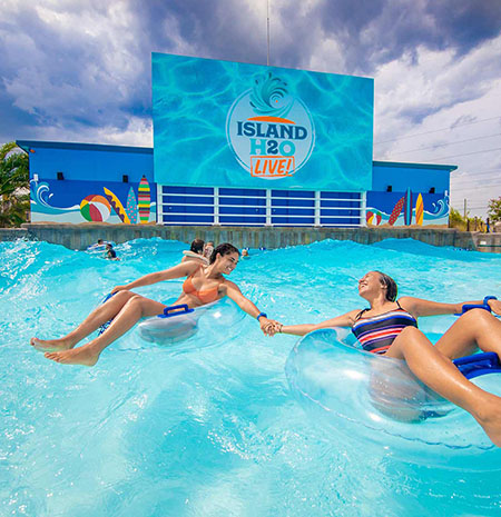 Friends holding hands while riding in tubes in the wave pool at Island H2O Water Park