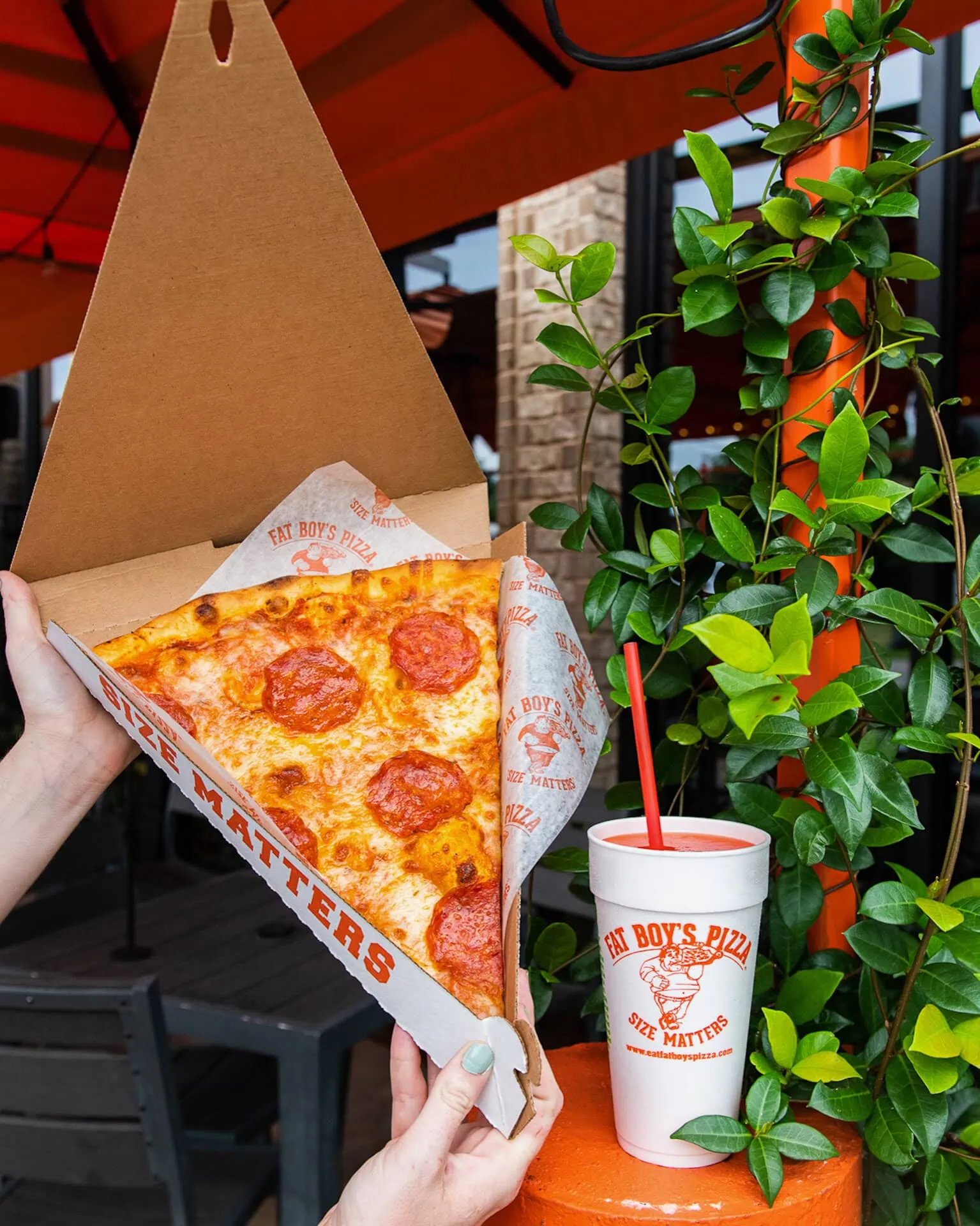 Large Fat Boy’s pepperoni pizza slice next to a drink cup