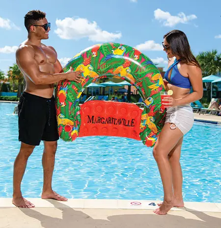 Couple holding a Margaritaville pool float at the edge of a resort pool