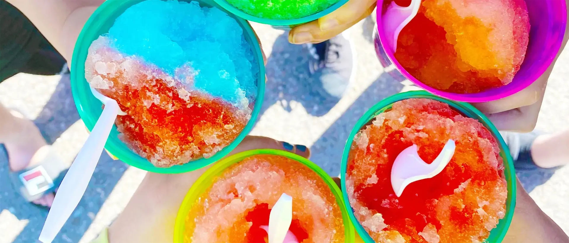 Manos sosteniendo conos de nieve de colores