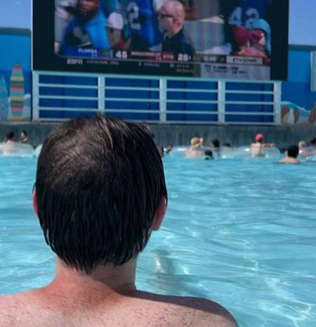 Man watching a football game from the wave pool at Island H2O Water Park