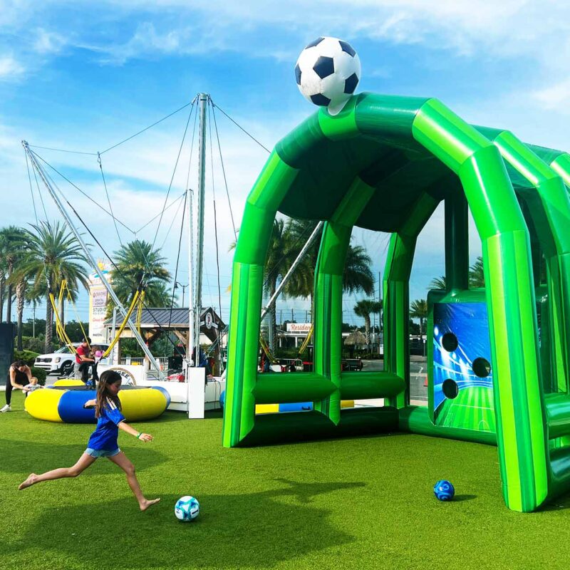 Young girl kicking a soccer ball into an inflatable goal game at Sunset Walk