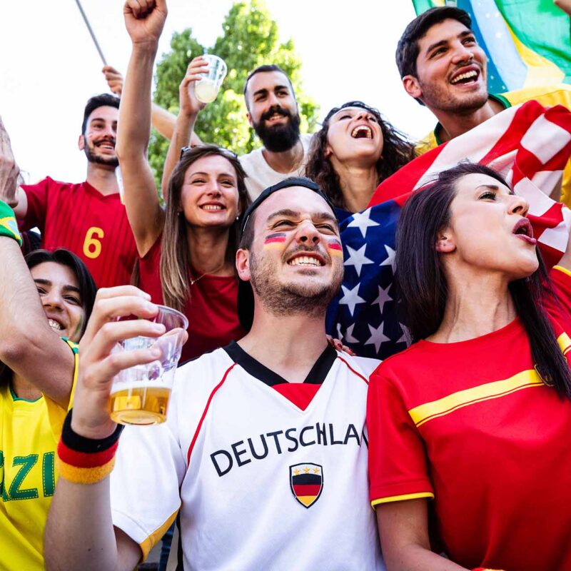 Group of people celebrating while wearing soccer jerseys from various countries